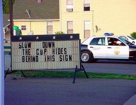 cop hides behind sign